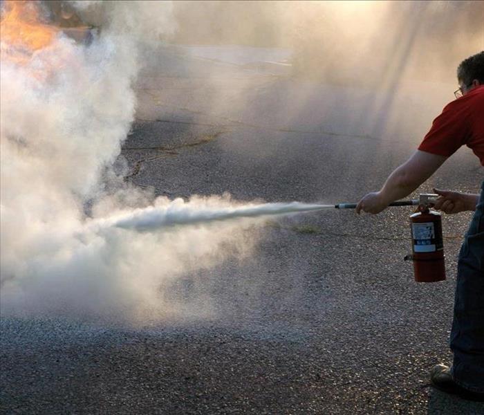 Image of a person using a fire extinguisher to put out a fire