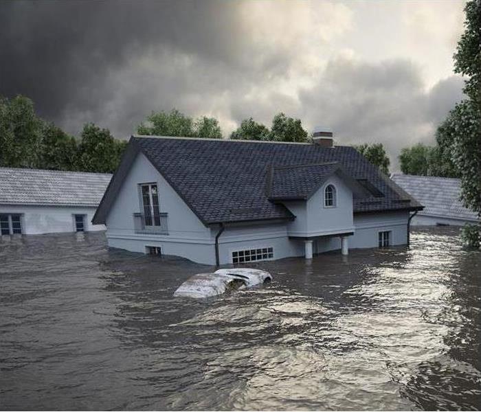 Image of severe flooding. Car is underwater and the house has water halfway up. 
