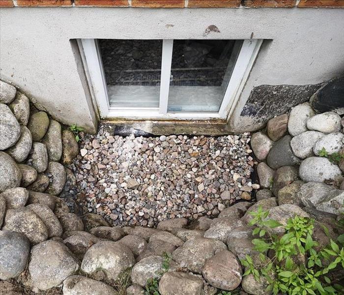 basement window with window well surrounded by rocks
