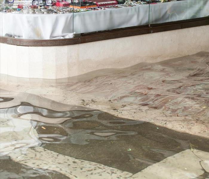 Image of a flooded street with water entering a store.